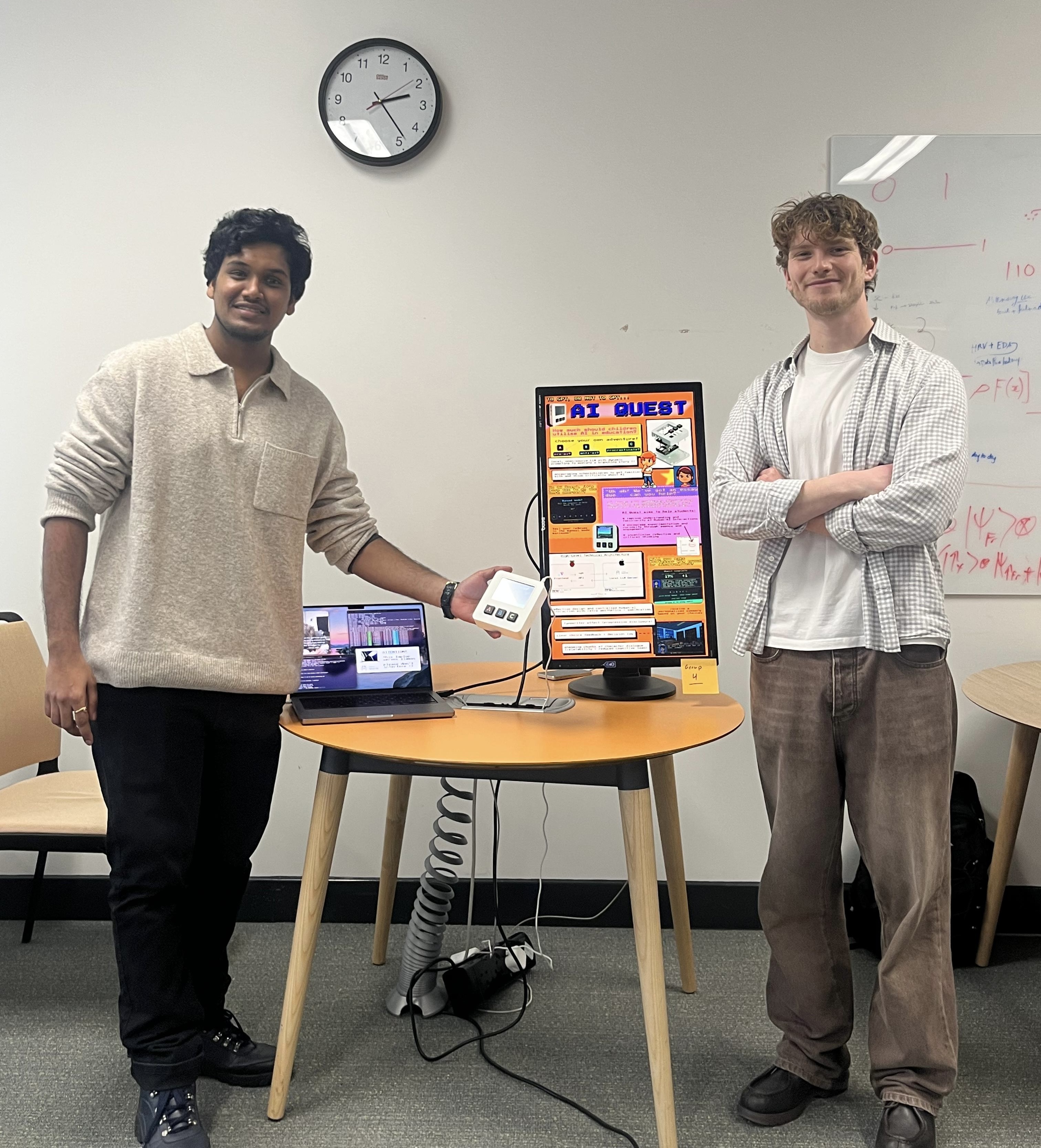 Callum and Srikar at the AI Quest demo desk, with the console, MacBook LLM server, and project poster on display